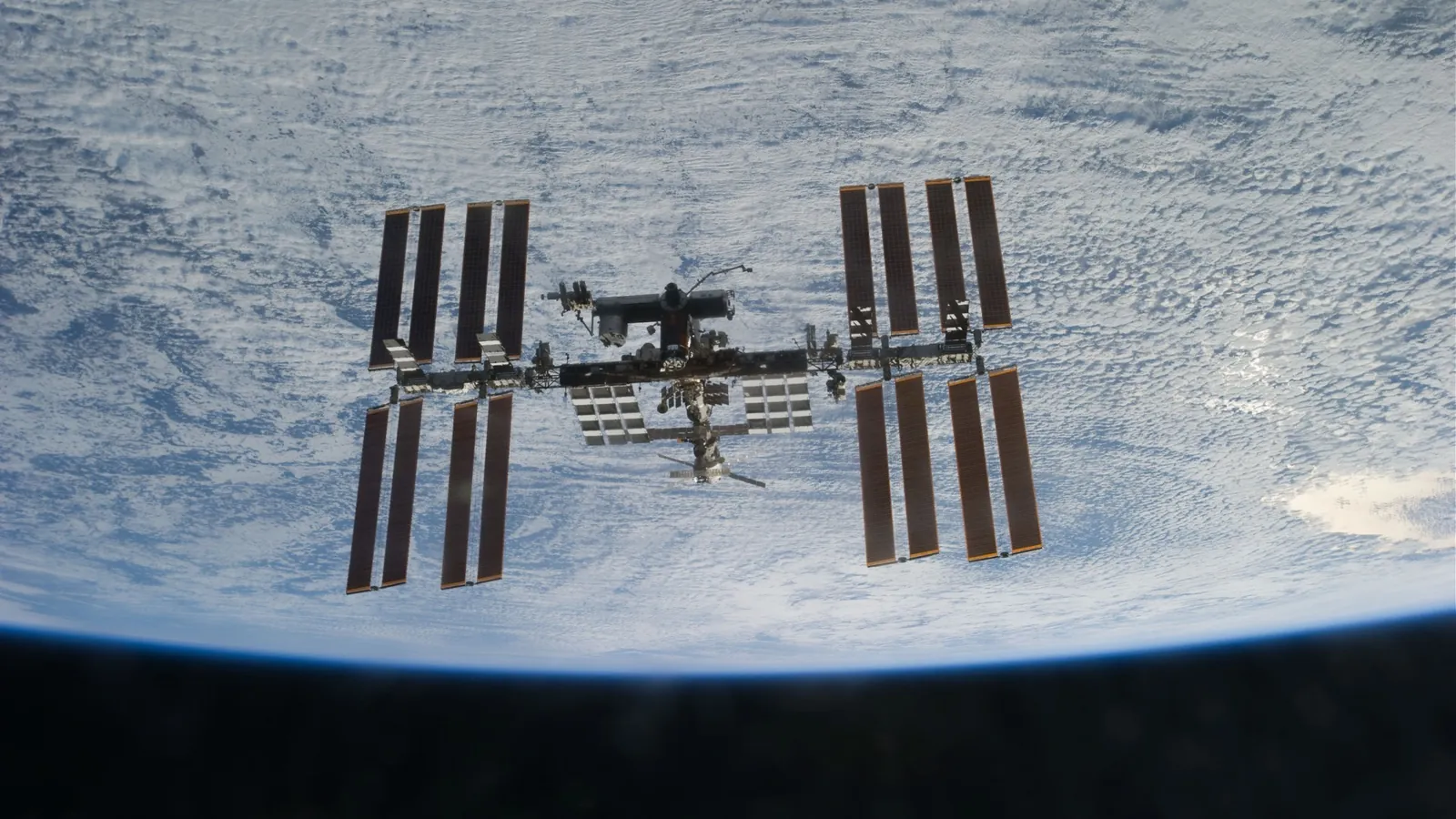 Real photo of the International Space Station above a sea of clouds, taken from a departing spacecraft