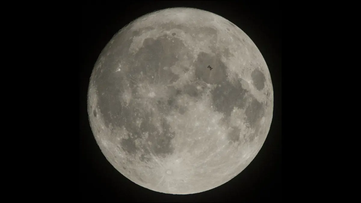 Real photo of the full Moon with a tiny dark shape in front of it: the space station